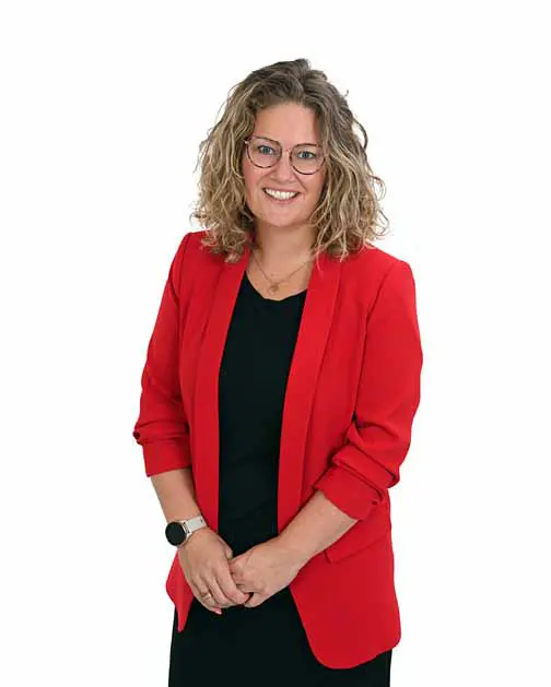 Lachende vrouw met krullen, met een zwart shirt en rood colbert, voor een witte achtergrond.