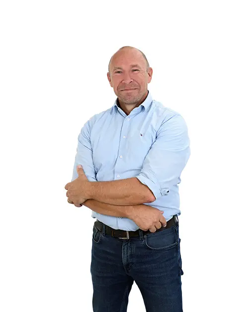 Man met lichtblauwe blouse met opgestroopte mouwen en gekruiste armen.