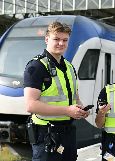 Jonge man in veiligheidshesje met telefoon in zijn hand.
