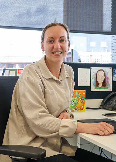 Vrouw met beige blouse aan een bureau.