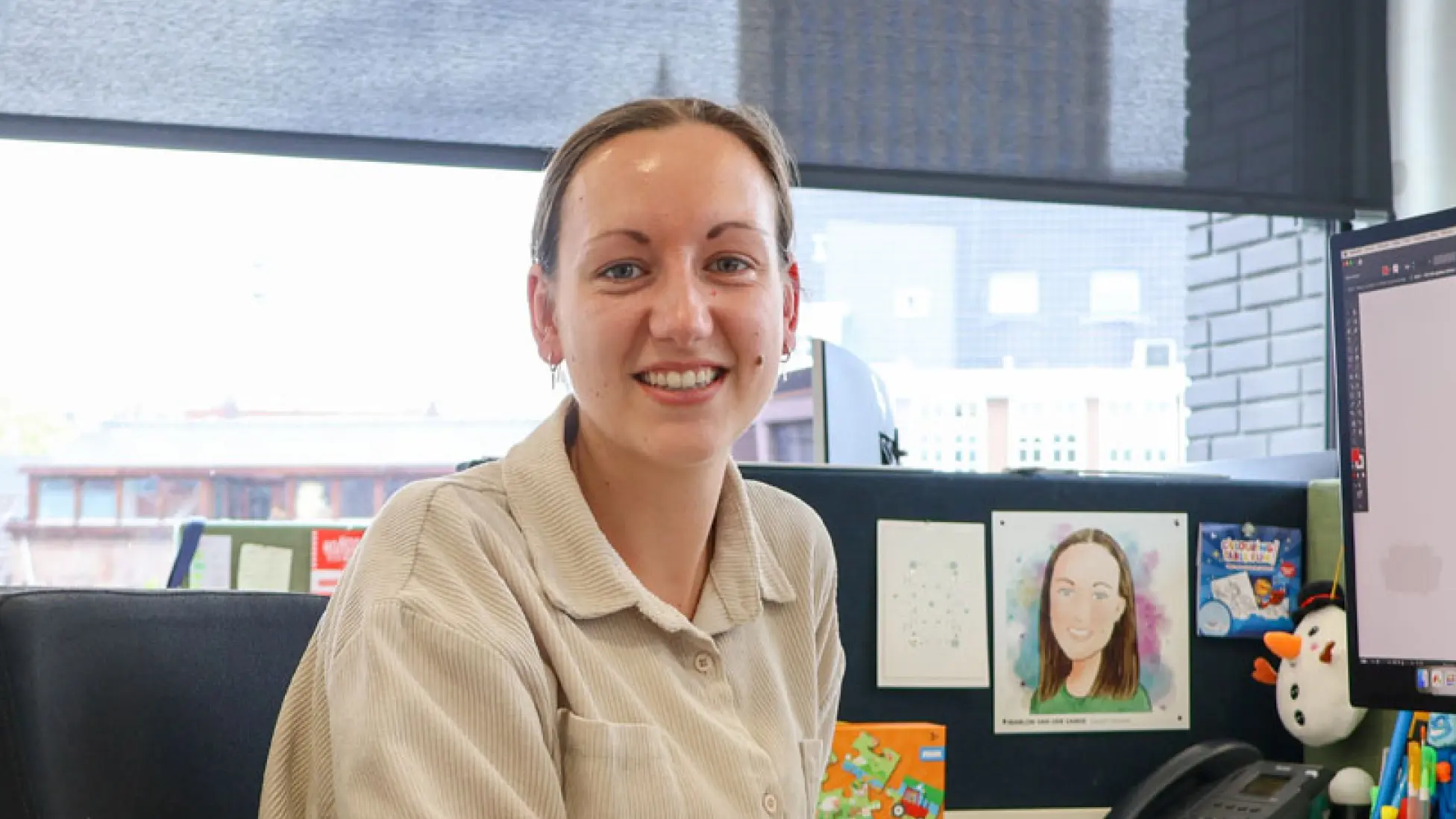Vrouw met beige blouse aan een bureau.