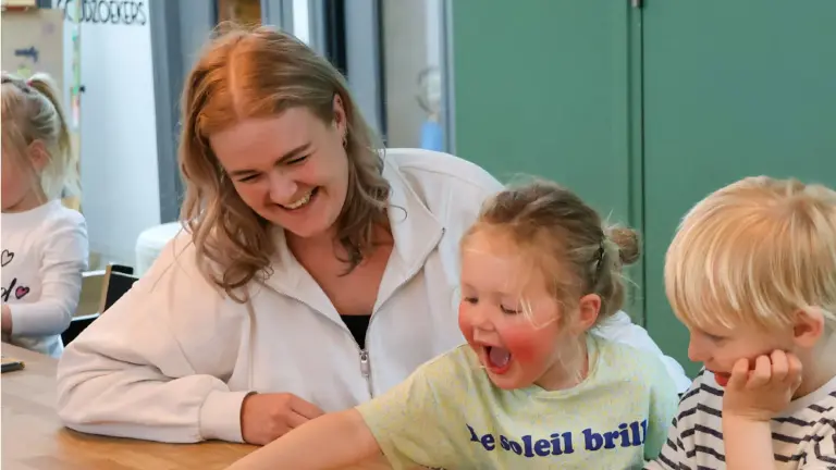 Lachende vrouw aan het spelen met kleine kinderen.