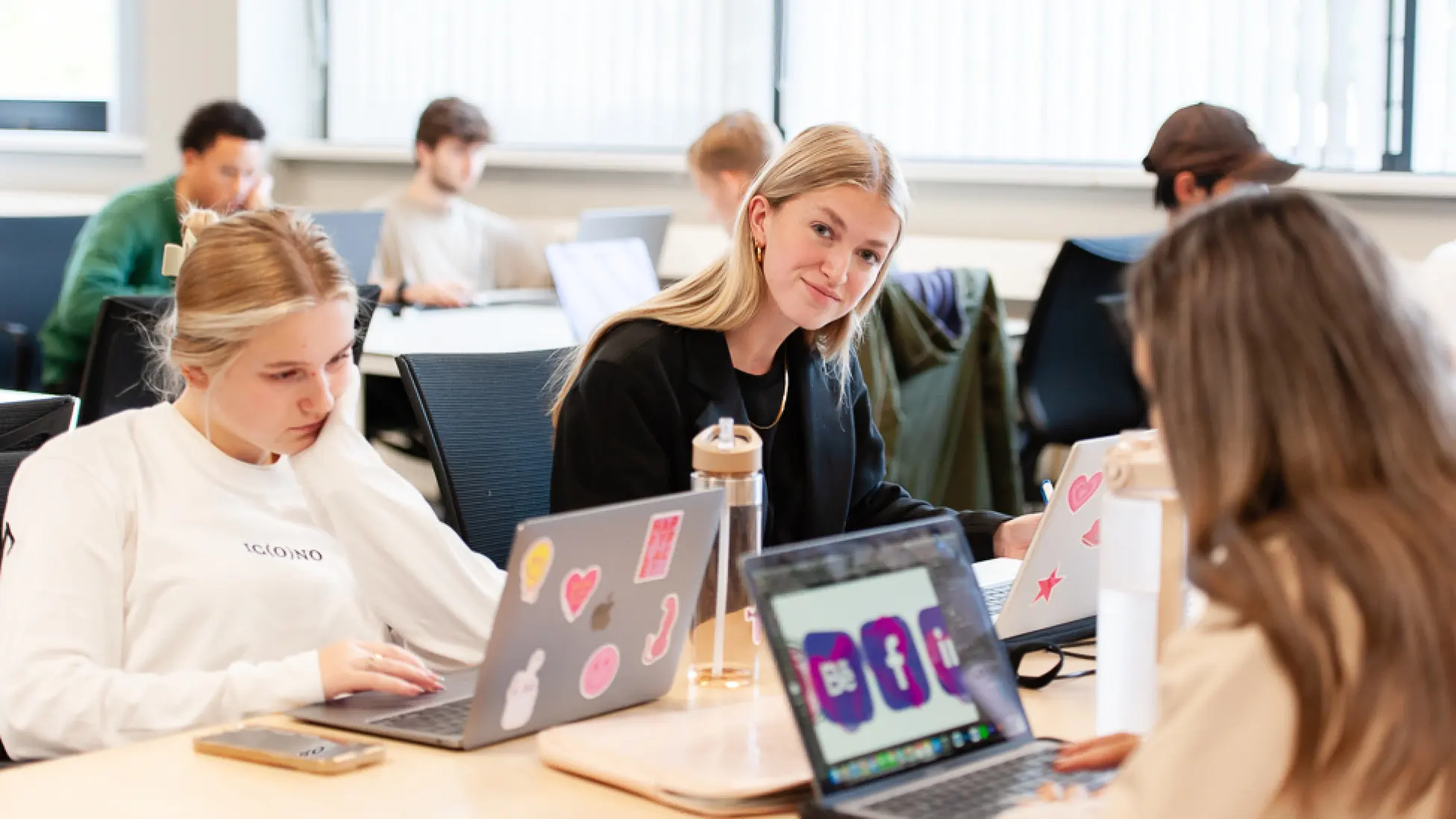 Klaslokaal met studenten die aan hun laptop werken.