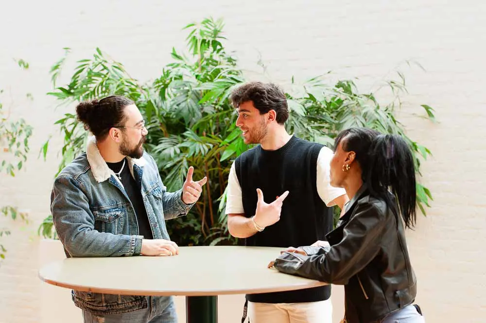 Drie personen staan rond een tafel.