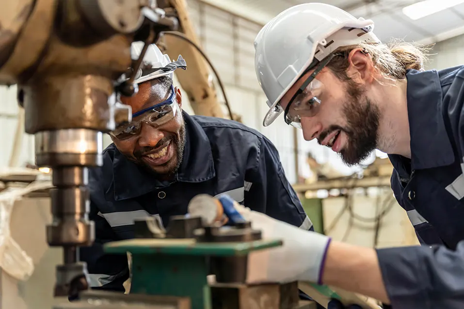 Twee personen zijn in een werkruimte aan het werk met verschillende onderdelen.
