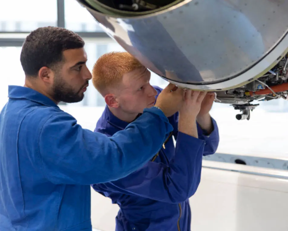 Twee jongens zijn in een blauwe overal aan het sleutelen aan apperatuur