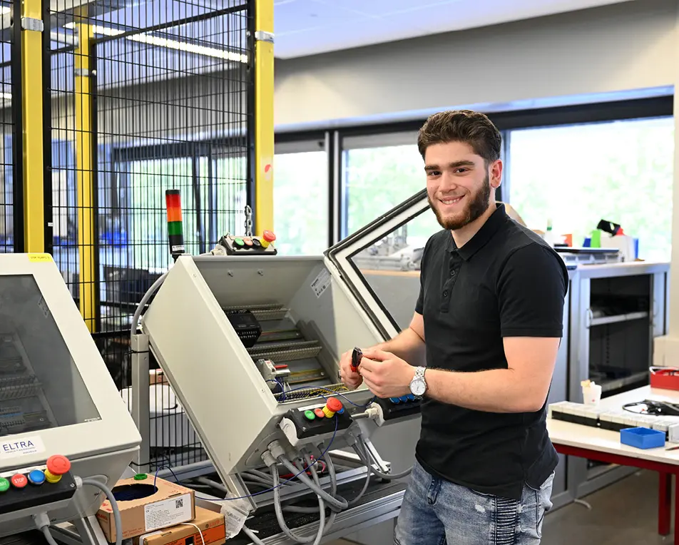 Vier personen staan rond industriële apparatuur in een technische of educatieve omgeving.