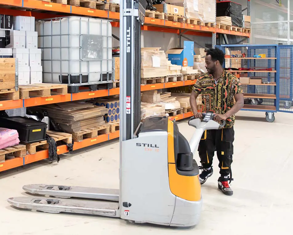 Man in gekleurde blouse aan het werk in een loods.