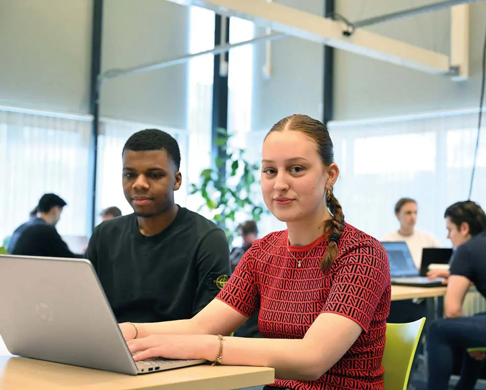 2 personen in een lokaal achter een laptop