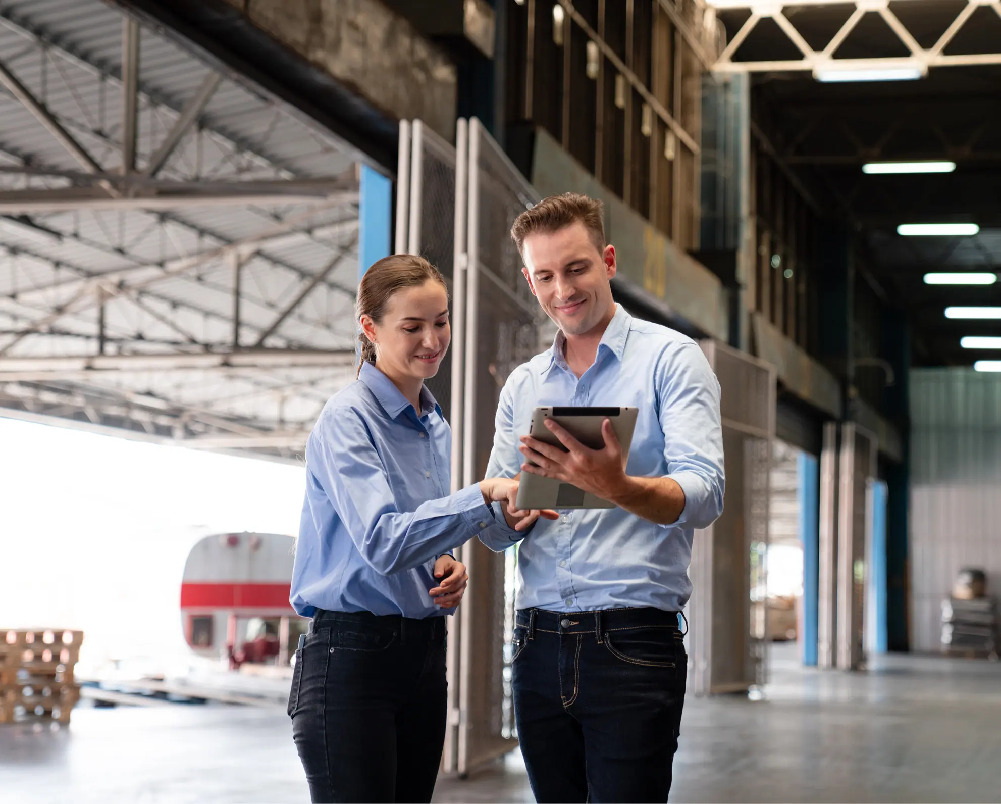 Twee personen in een industriële omgeving dragen lichtblauwe shirts en donkere broeken