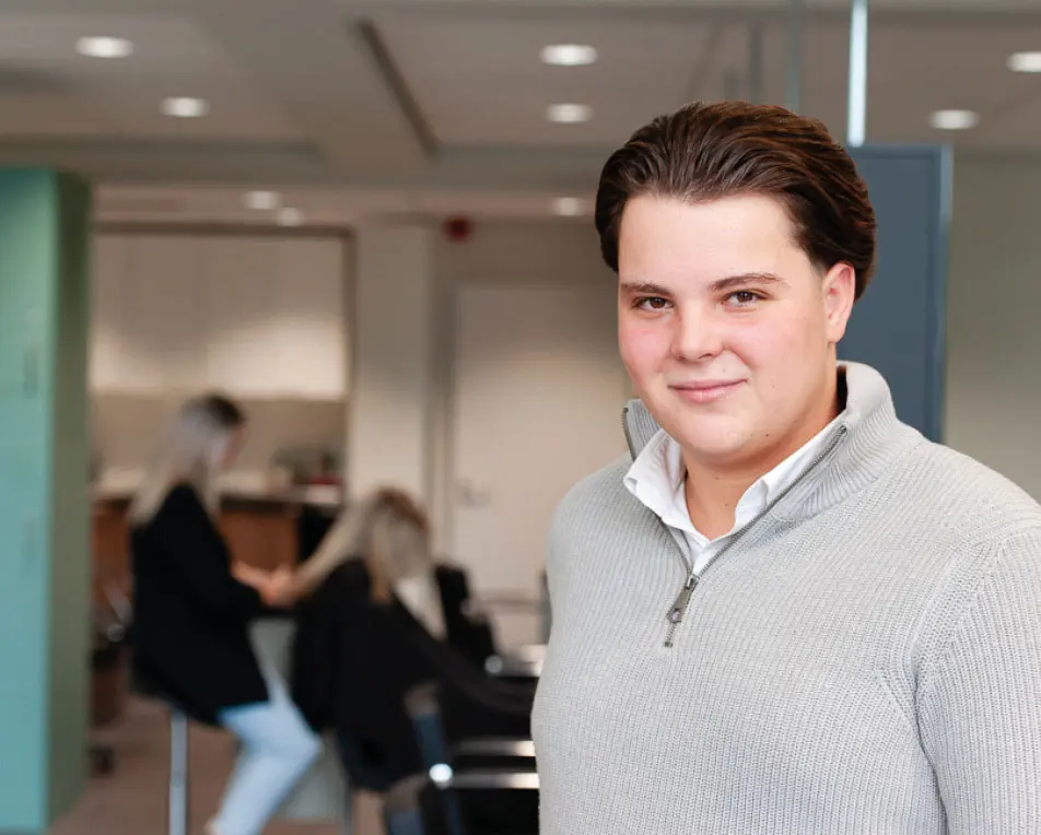 jongeman in een salon, op de achtergrond word er iemand geknipt