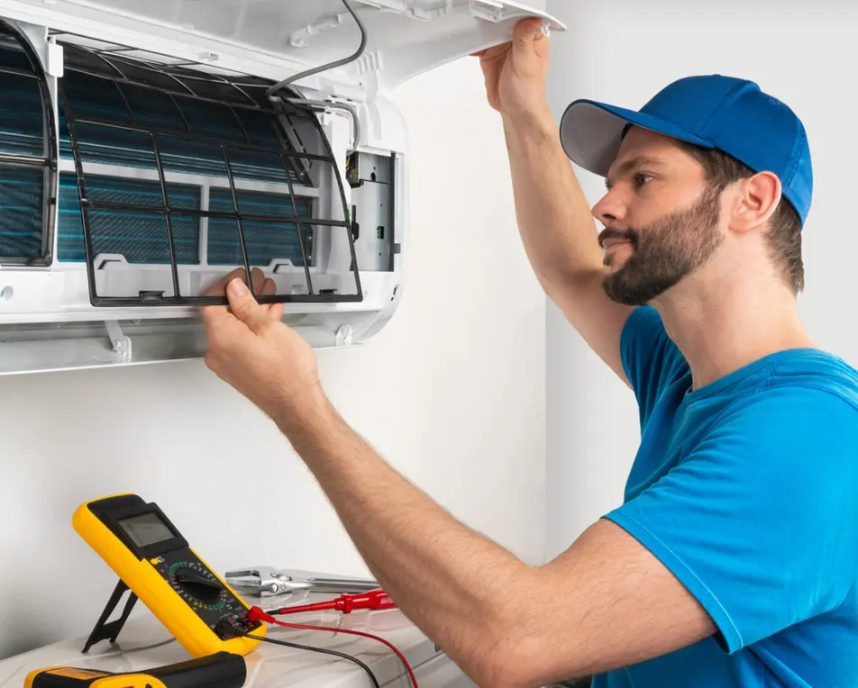 Man in blauwe outfit is een airco aan het repareren.