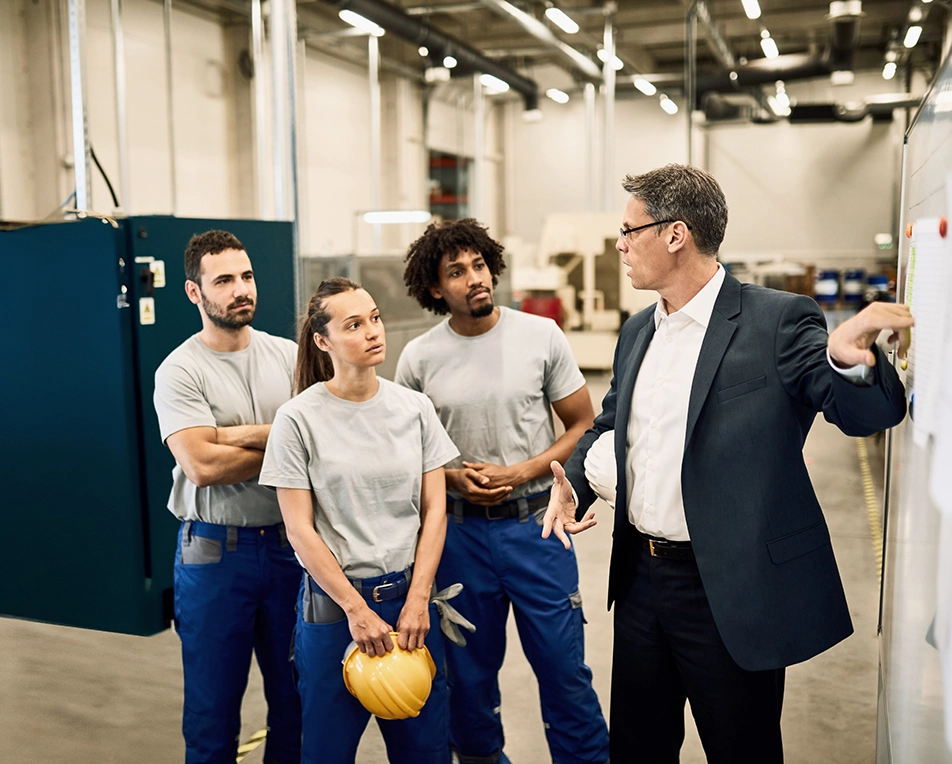 Leidinggevende in fabriekshal die zijn medewerkers op iets wijst.