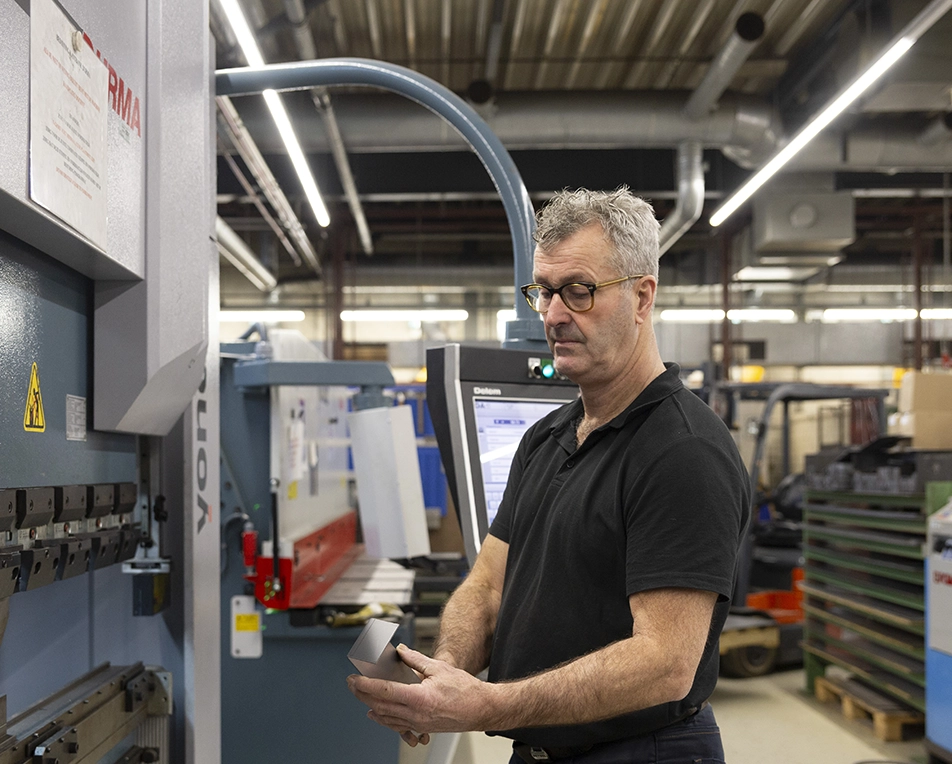 Man aan grote machine voor productietechniek plaatwerk