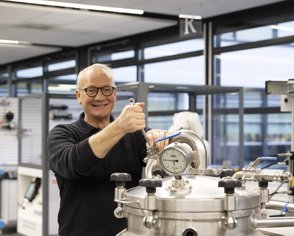 Man met bril die aan een ketel sleutelt