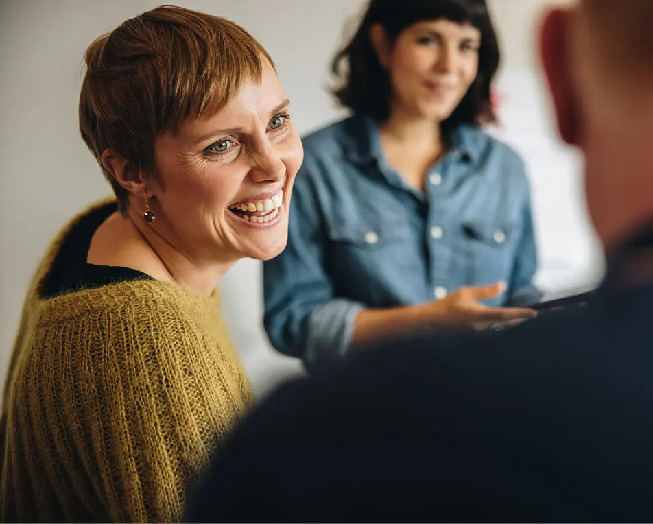 Vrouw in groene trui lacht naar man met donkere kleding.