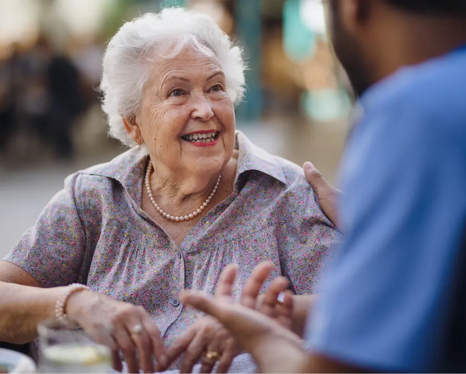 Oudere vrouw in een gesprek met een man met een blauw shirt.