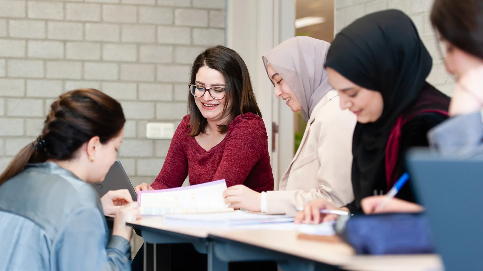 Vier personen zitten rond een tafel in gesprek of overleg, met vervaagde gezichten voor privacy