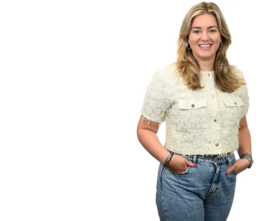 Blonde vrouw met spijkerbroek en witte top.