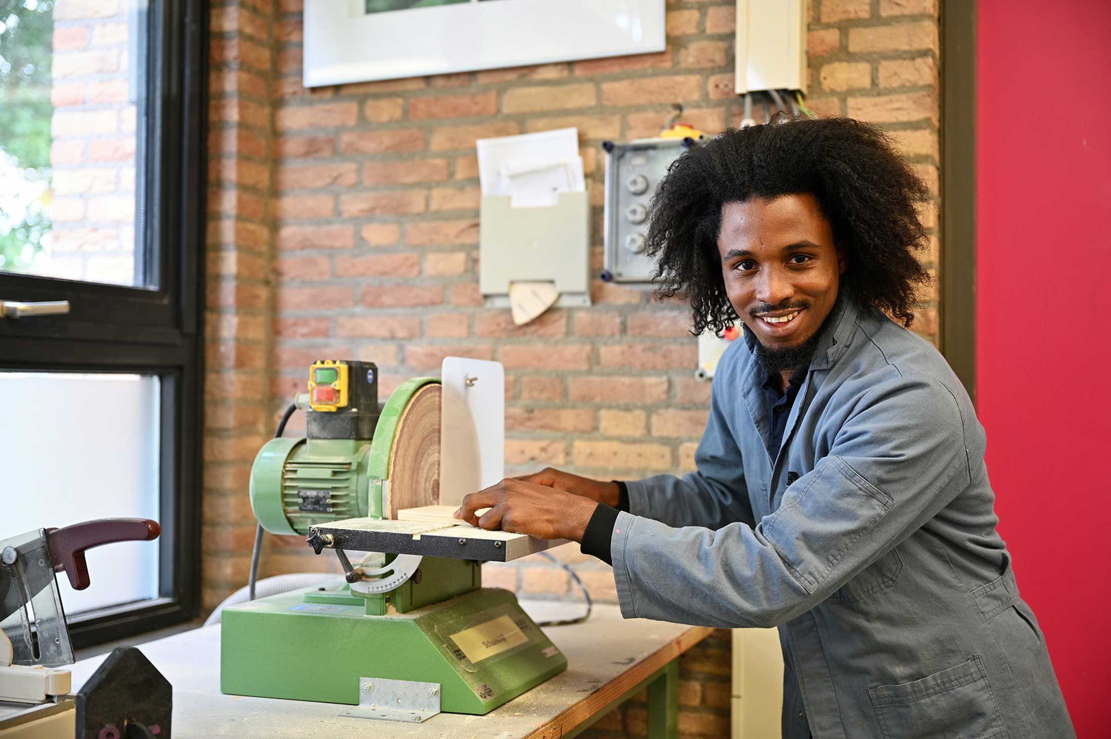 Man in werkjas werkt in een werkruimte met een stuk hout.
