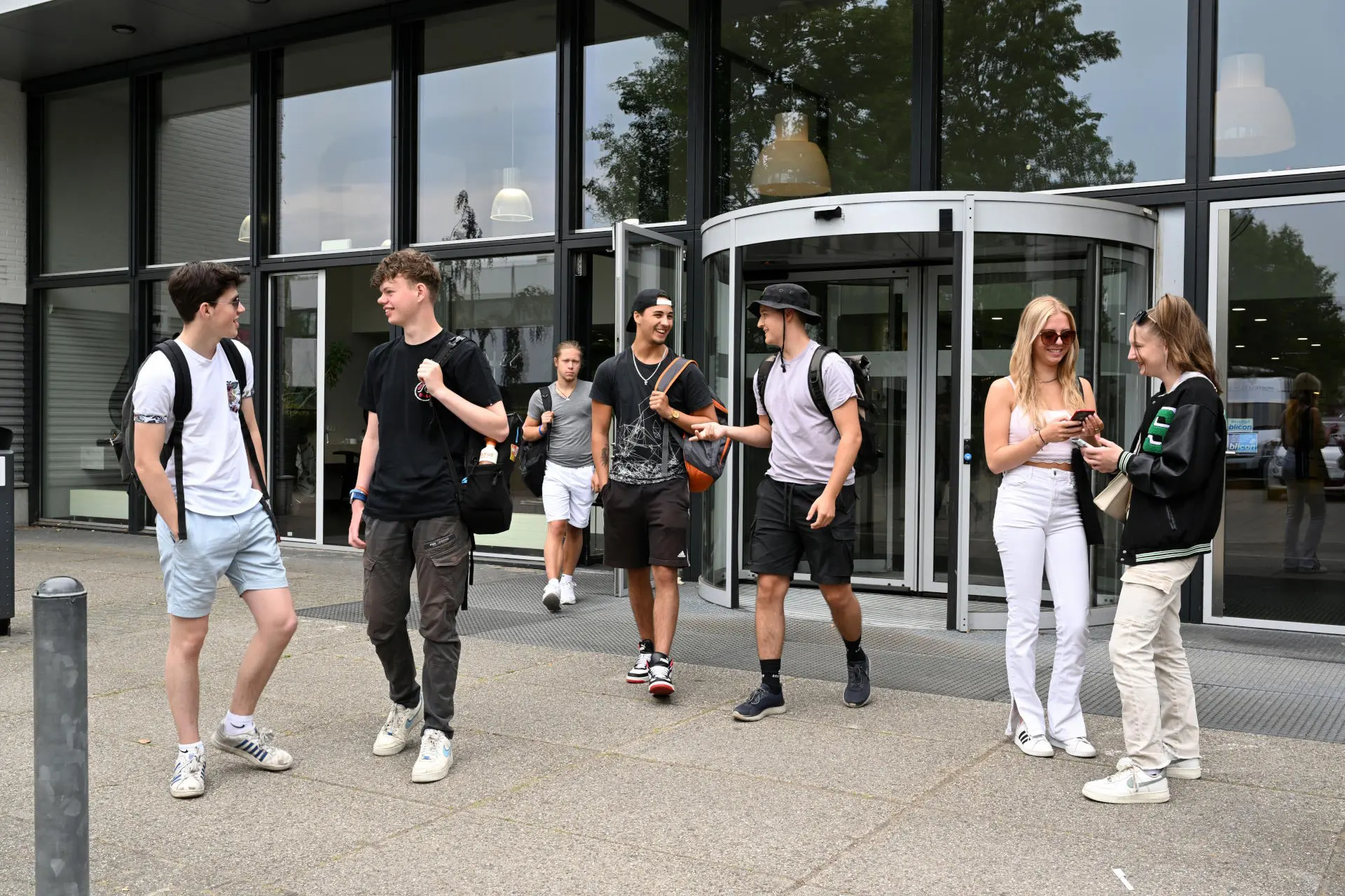 Jongeren voor een gebouw met veel ramen.