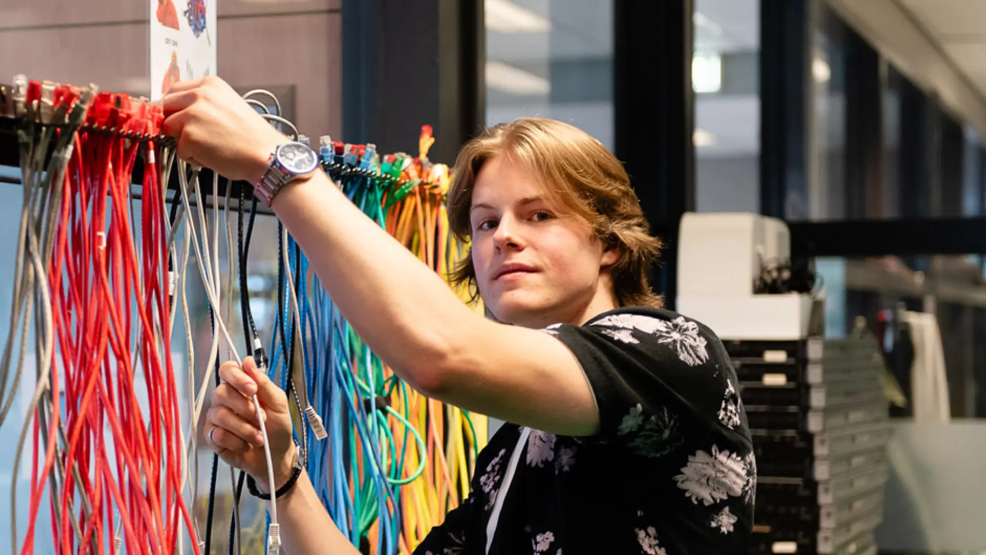 Jongen staat met gekleurde kabels.