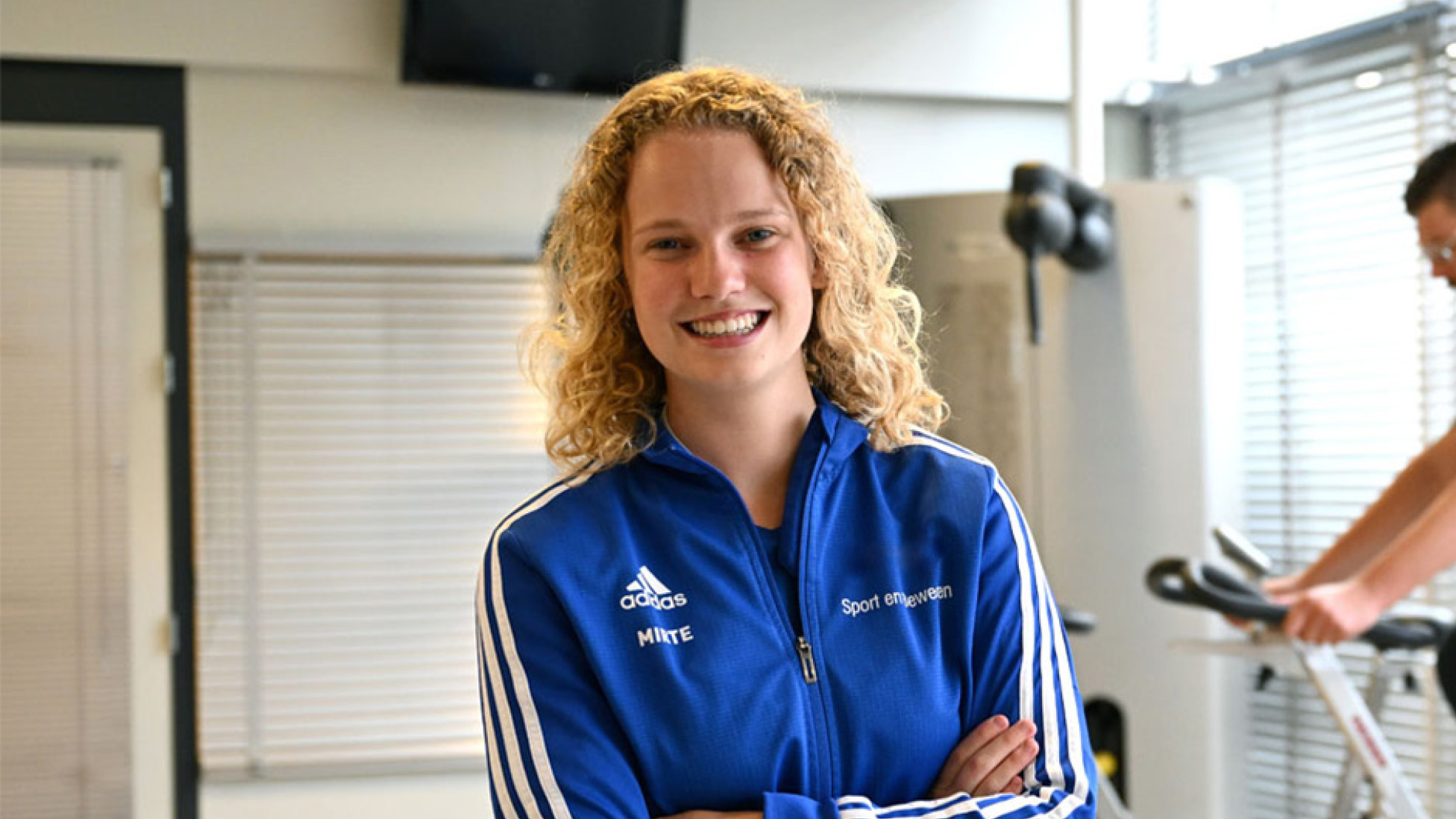 Vrouw in sportschool met een blauw vest aan.