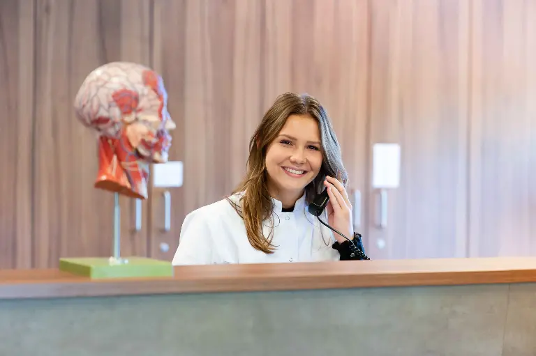 Jonge dame zit achter balie en is aan het bellen.