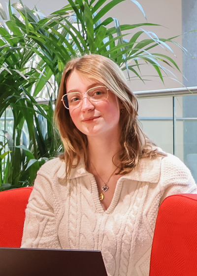 Vrouw met wollen trui, zittend in een rode bank.