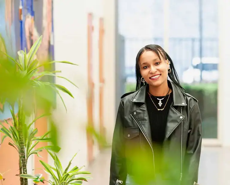 Vrouw met lerenjas in een lichte ruimte.