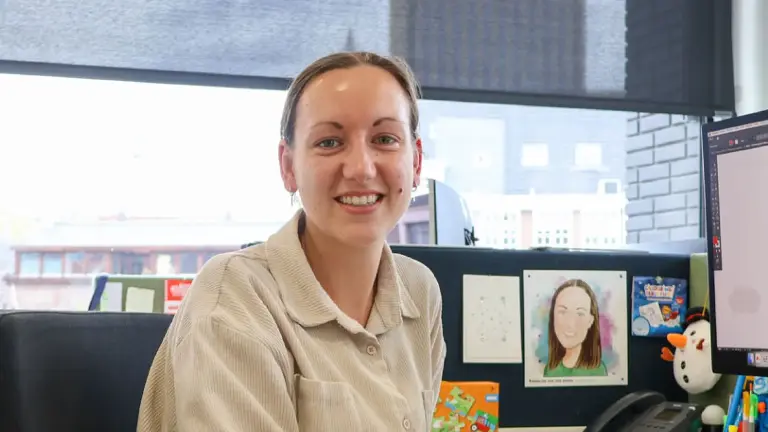 Vrouw met beige blouse met tekeningen op de achtergrond.
