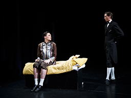 2 studenten artiest op het podium van het theater, een staat achter een bed de ander zit op het bed